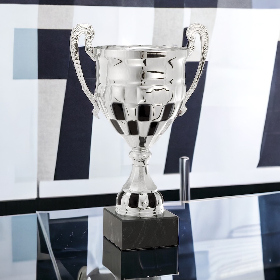 A racing trophy made with a silver metal cup that has a checkered flag design at the bottom. It's mounted on a black marble base that includes an engraving plate for personalization.