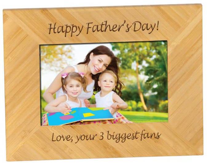 A bamboo picture frame that holds a 4x6 photo. The photo features a mother and her two children. The top of the frame has the words, "Happy Father's Day" laser engraved into it. The bottom says, "Love, your 3 biggest fans"
