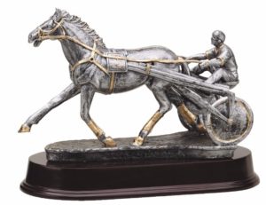 A resin statue that features a race horse & jockey using a sulky during a race. It's mounted on a dark maroon base.