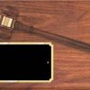 A walnut finished board with a walnut gavel & gold gavel band. The gavel slants from top left to middle right. Below the hammer of the gavel is a black engraving plate with notched corners & a gold border.