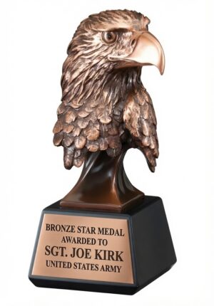 A realistic bronze-finished bald eagle head sculpture with highly detailed feather textures, sharp beak, and a commanding, forward-gazing expression. The bust is mounted on a sleek black tapered base with a large gold/brass engraving plate that reads: 'BRONZE STAR MEDAL AWARDED TO SGT. JOE KIRK UNITED STATES ARMY.' This patriotic award symbolizes strength, courage, and military valor.