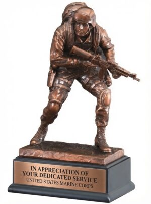 USMC Marine Statue RFB135 featuring a highly detailed bronze resin Marine in full combat gear, holding a rifle in a dynamic ready stance. The figure stands on a textured bronze base mounted on a solid black pedestal with a full-width copper engraving plate that reads 'IN APPRECIATION OF YOUR DEDICATED SERVICE UNITED STATES MARINE CORPS' in black lettering. This 10-inch tall military recognition award honors courage, dedication, and service to the United States Marine Corps.
