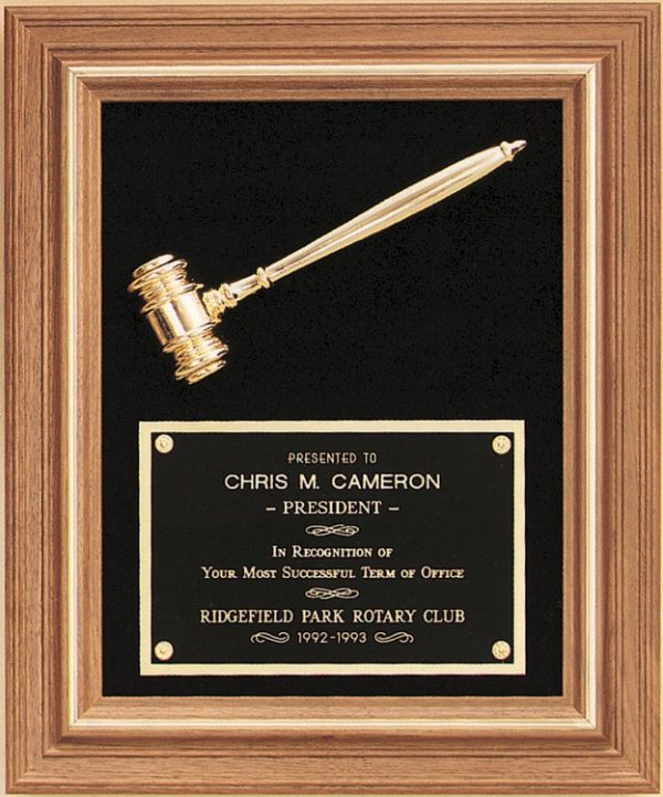 An American walnut wood frame with a gold metal inlay for decoration. The inside features a black velour background with a gold metal gavel at the top and a black brass plate at the bottom. The black engraving plate has words of recognition for a Rotary Club President.