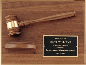 A walnut board with a walnut gavel & sounding block as decoration. In the bottom right hand corner is a black brass engraving plate with words of appreciation for a board chairman.