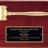 A piano finished rosewood board with a gold metal gavel at the top and a black brass engraving plate at the bottom. The engraving plate has text about the Lawyer of the Year given by the Illinois State Bar Association.