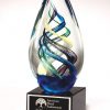 Glass egg award with blue, green & yellow colors swirled in the middle, mounted on a black base, 1610, 7" tall