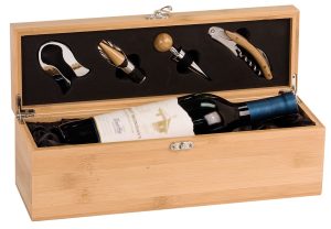 A wine box made out of bamboo that has silver hinges & latches. The inside of the box is lined with black satin & holds a bottle of wine. The inside of the lid has wine tools from left to right: A foil cutter, decanting pourer stopper & cork screw.