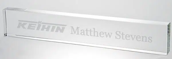 Our Crystal Name Plate features a rectangle piece of 3/4" thick clear crystal. This C1040 crystal nameplate measures 2.25" x 12" in size and weighs 2.6 lbs. This particular name plate is laser engraved with a company logo on the left for Keihin Corporation and Matthew Stevens name to the right of it.