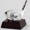 A golf trophy featuring a silver golf driver head & silver golf ball mounted on a dark wood base.