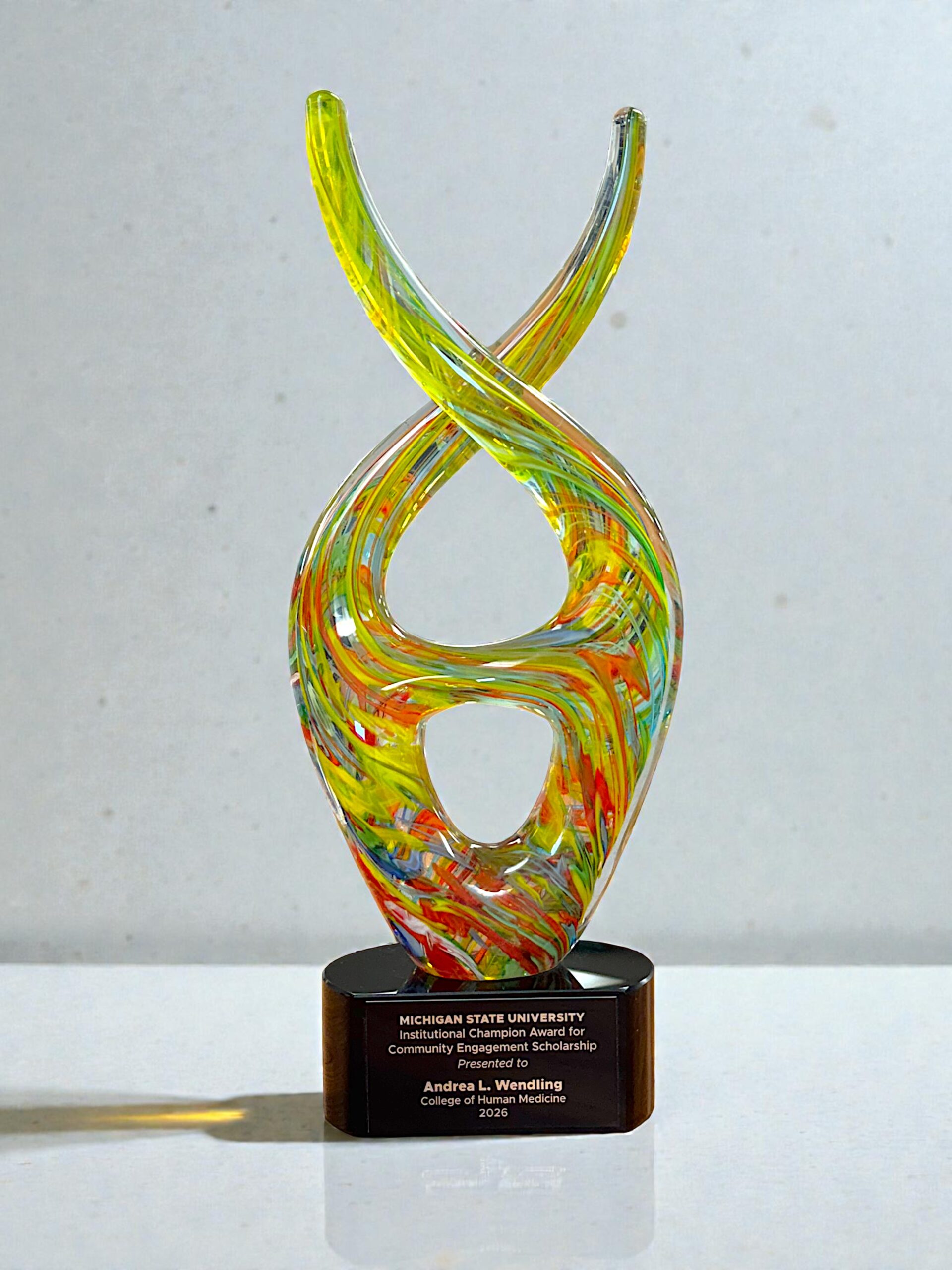 Our Color Twist Glass Art Award is mounted on a black glass base with a black & gold engraving plate for personalization. The AGS22 5.75" by 14.5". THe photo shows the front of the item. This item comes packaged in a satin lined, deluxe gift box.