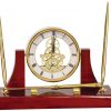 An Executive Gold Clock Desk Set. It's made with rosewood that's coated with a glossy piano finish. It features 2 gold pens, a letter opener & a gold skeleton clock.