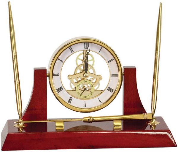 An Executive Gold Clock Desk Set. It's made with rosewood that's coated with a glossy piano finish. It features 2 gold pens, a letter opener & a gold skeleton clock.