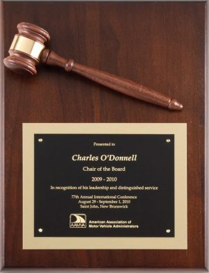 A 9x12 walnut board with a walnut gavel & a gold gavel band at the top. At the bottom is a black engraving plate with a gold backer. The engraving is recognition for the Chair of the Board for the AAMVA.