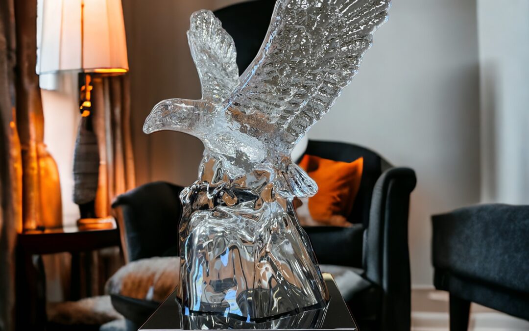 Our Crystal Eagle Statue features a clear crystal eagle with his eagles spread wide mounted on a black base. The base includes a black & silver engraving plate with personalization on it. This K9117 eagle statue is sitting on a wood desk in front of a chair & lamp.