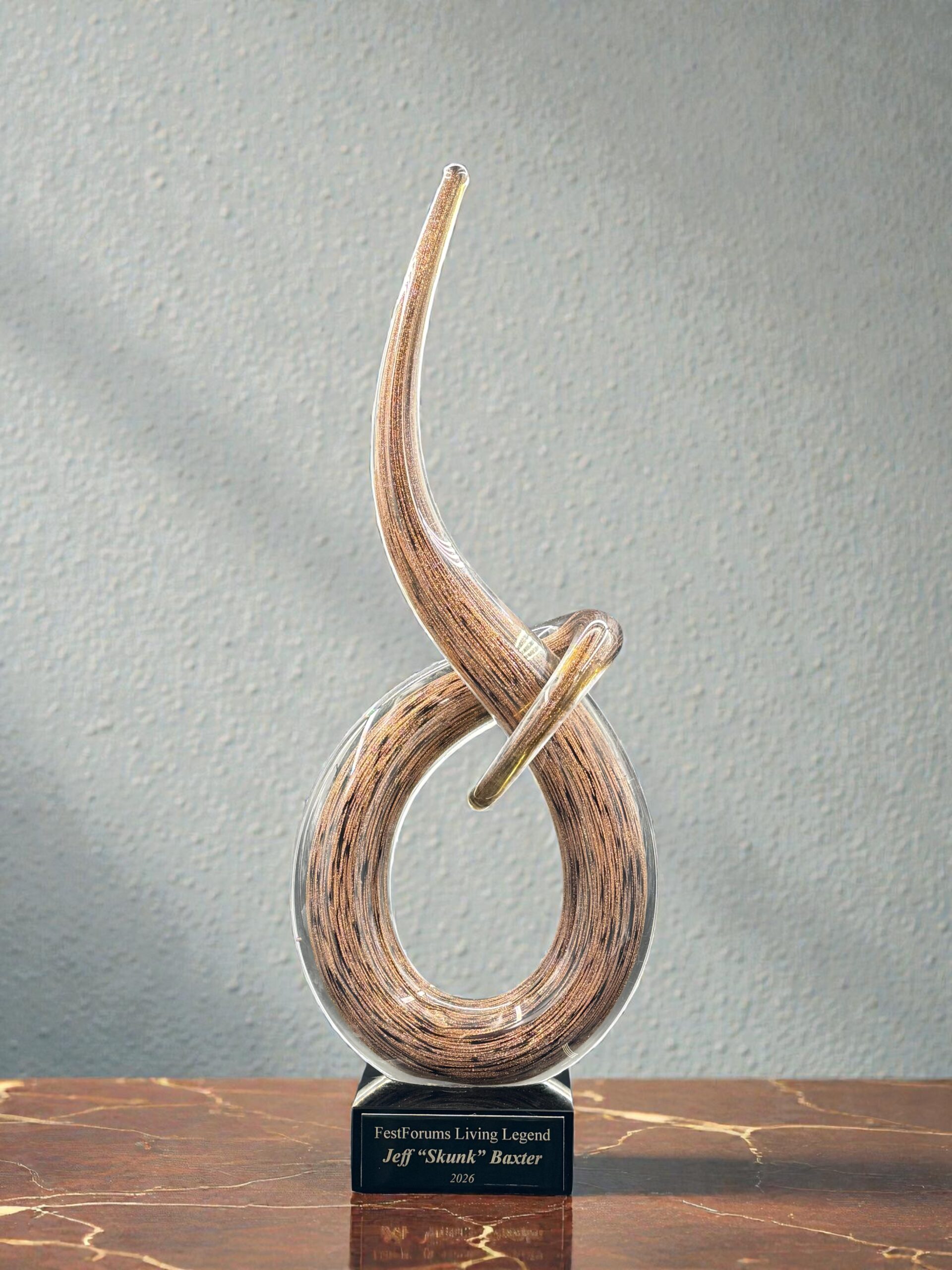 Our Brown Swoop Art Glass Award features a unique, swooping piece of brown art glass mounted on a black glass base with a black & gold engraving plate for personalization. THis photo shows the front of the item. This item comes in two different sizes, the GLSC54 which is 4" by 10" and the GLSC55 which is 6" by 14.5".