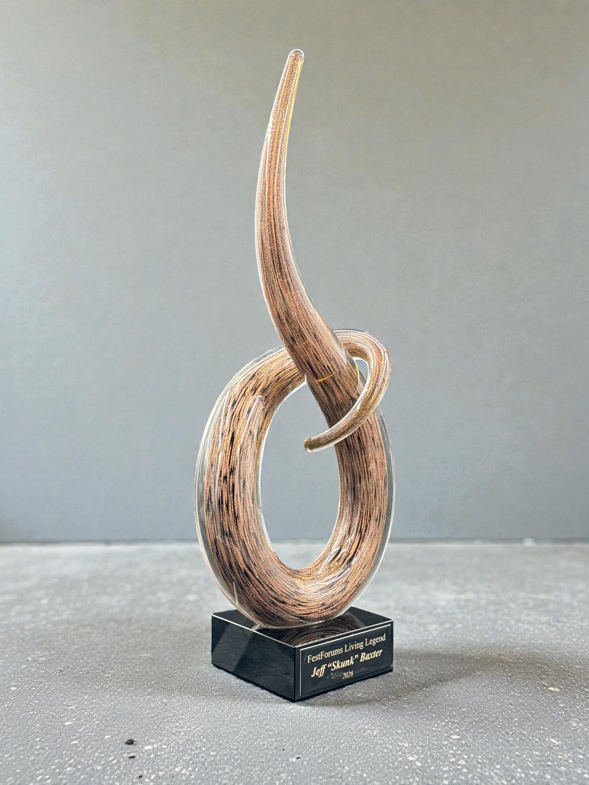 Our Brown Swoop Art Glass Award features a unique, swooping piece of brown art glass mounted on a black glass base with a black & gold engraving plate for personalization. This photo shows the item at an angle. This item comes in two different sizes, the GLSC54 which is 4" by 10" and the GLSC55 which is 6" by 14.5".