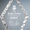 A diamond shaped glass award with a diamond stainless steel look around the edges. The inside has laser engraving of an old radio microphone. It's an award for Best Radio Host in the Midwest. The clear glass piece is mounted on a black glass base.