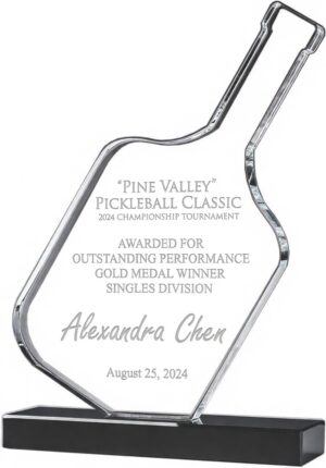 A photo of our Pickleball Paddle Trophy. It features a clear crystal pickleball paddle for laser engraving personalization mounted on a black crystal base. This one is personalized with words of recognition for Alexandra Chen winning the Pine Valley Pickleball Classic on August 25, 2024.