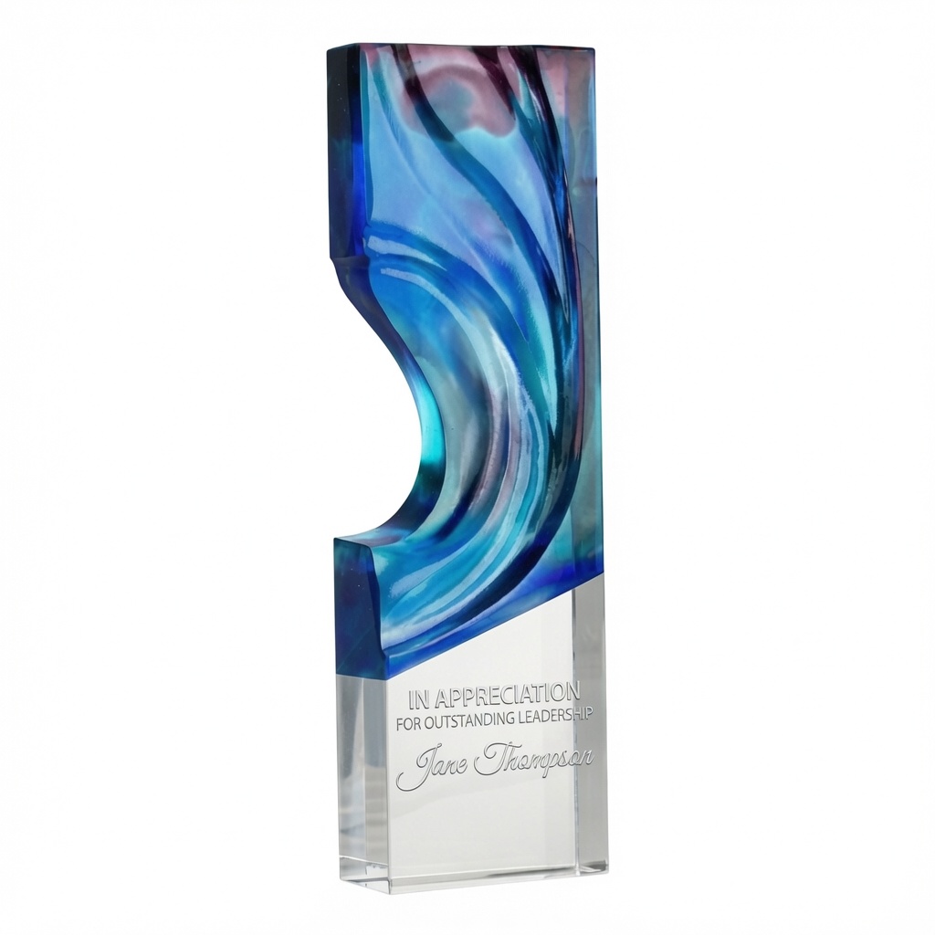 Arctic Wave Award (C2501) – a striking 9-5/8 inch tall optic crystal trophy featuring a vibrant blue and purple pâte de verre wave design that flows through a modern sculpted cutout. The clear rectangular base includes elegant frosted white laser engraving that reads “IN APPRECIATION FOR OUTSTANDING LEADERSHIP” and “Jane Thompson”. This premium 3.1 lb crystal award symbolizes inspiration, endurance, and achievement. Shown on a pure white background.