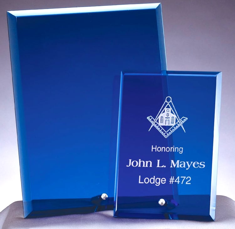 2 sizes of blue glass plaques are shown. The larger 8x10 size is on the left and it's blank, while the smaller 6x8 size is on the right. It shows how one looks with a laser engraved logo & text.