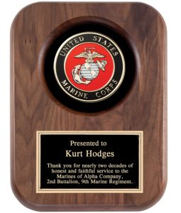 A solid walnut plaque with the marine corps seal at the top and a black & gold engraving plate at the bottom. The engraving talks recognizes a Marine for giving 20 years to the service.