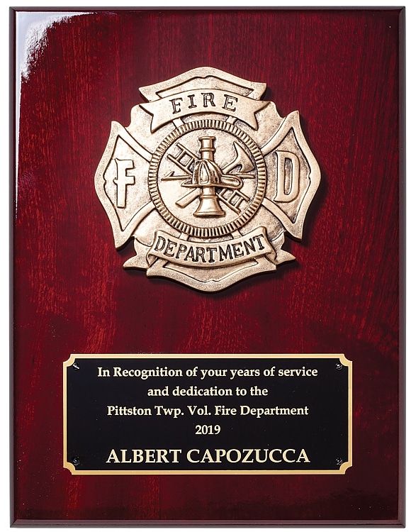 A rosewood plaque with a cast metal firefighter Maltese cross symbol at the top. At the bottom is a black & gold engraving plate for personalization. It features words of recognition for a firefighter who gave years of service at the Pittston Township Volunteer Fire Department.