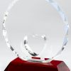 Round crystal award with a heart cut out at the bottom & hands etched around the heart. It's mounted on a red crystal base.