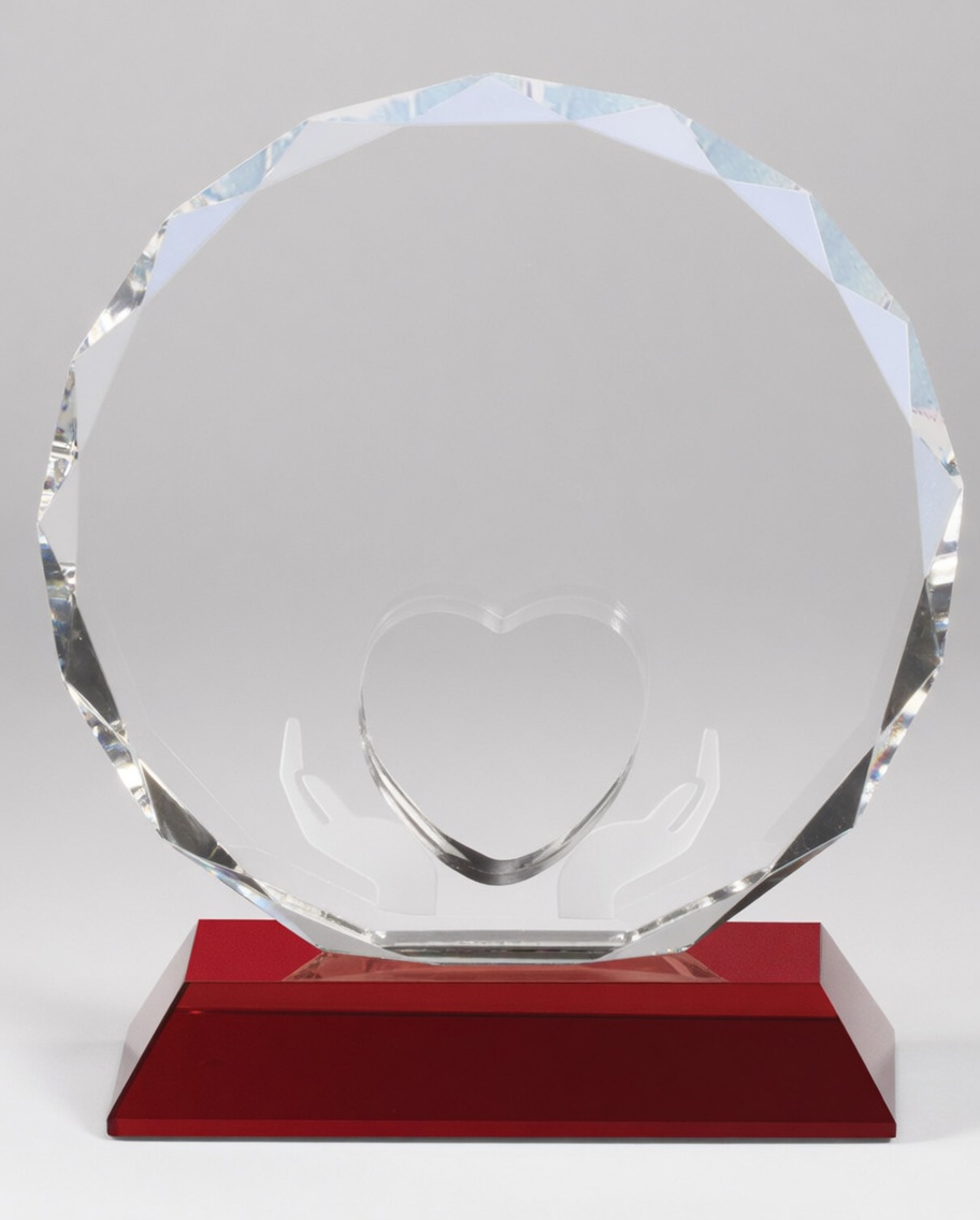 Beautiful round faceted crystal trophy featuring an elegant engraving of two hands gently holding a heart. Mounted on a vibrant red crystal base, this heartfelt award is perfect for appreciation, service milestones, volunteer recognition, and special personal or corporate gifts.