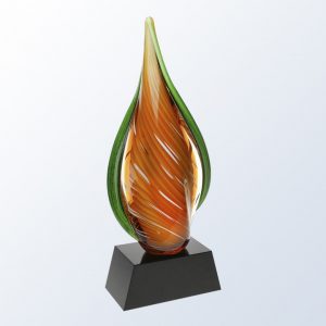Art glass piece with swirls of orange in the middle and green accents on the outside edges. It's mounted on a black glass base with an engraving plate for personalization.