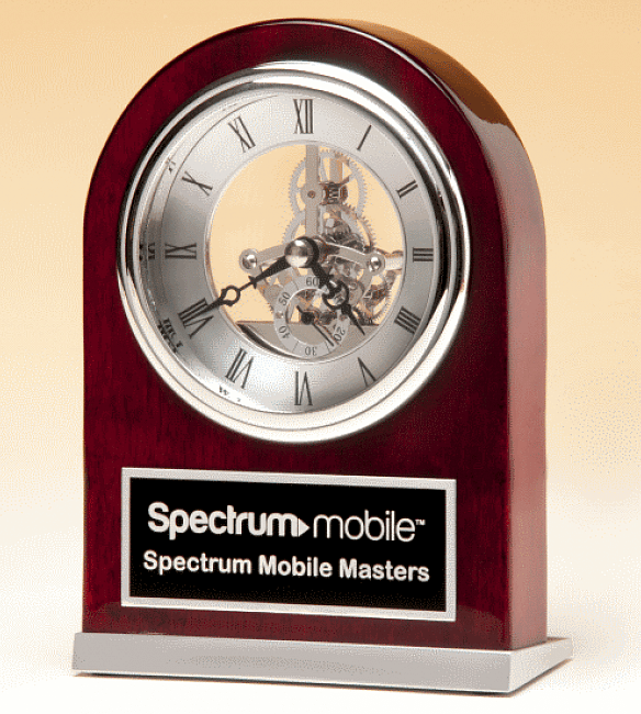 A domed rosewood case with a silver skeleton clock inside it towards the top. Below is a black & silver engraving plate with the Spectrum Mobile company logo. The base is made of silver aluminum.