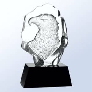 A piece of jaded crystal with an eagle bust head carved out in the back. It's mounted on a black crystal base.