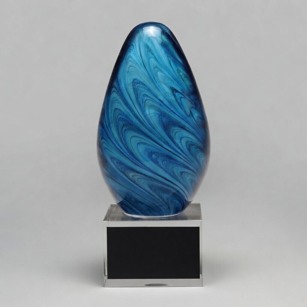 A striking hand-blown art glass trophy with vibrant blue swirling marble patterns in an elegant egg shape. Mounted on a clear acrylic base with a black engraving plate, this modern piece is perfect for personalized awards and recognition.