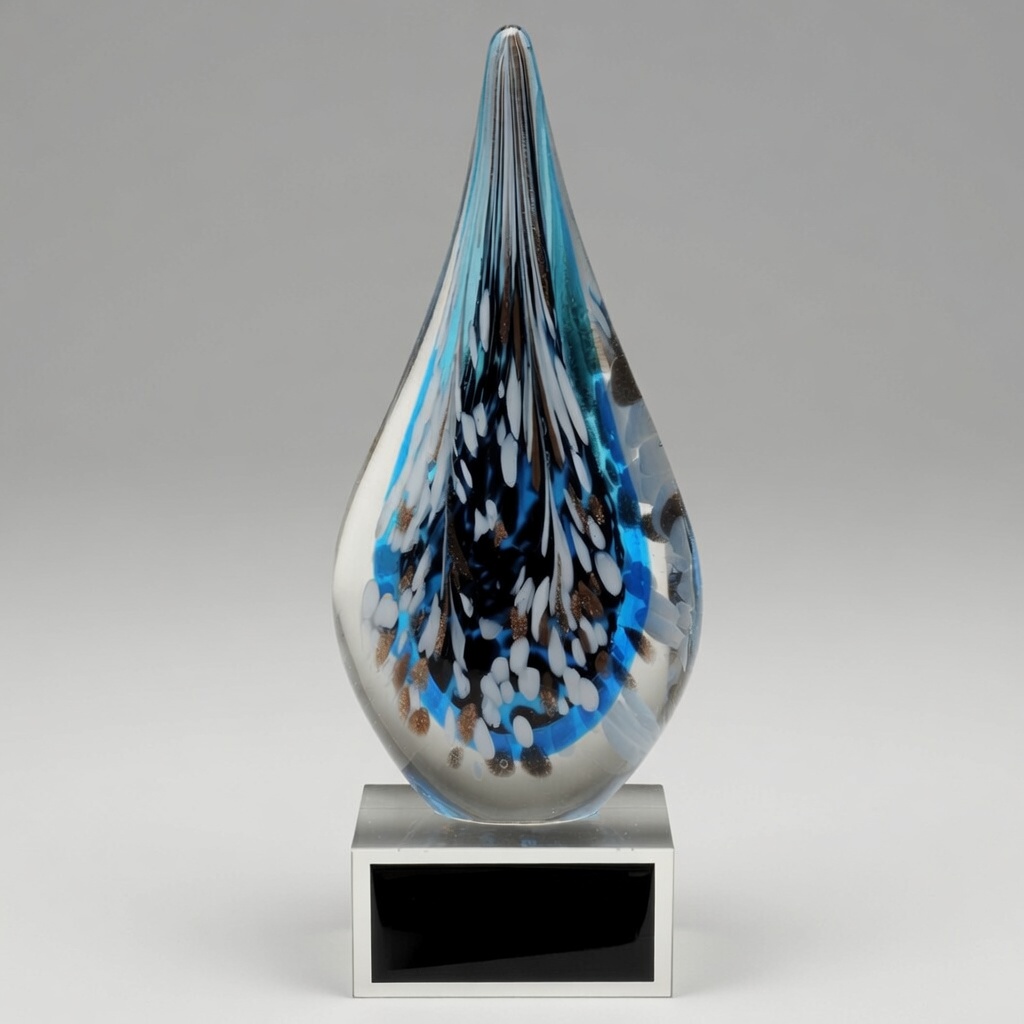 A striking hand-blown art glass trophy in a tall teardrop shape with vibrant blue, black, white, and gold speckled patterns. Mounted on a clear acrylic base with a black engraving plate, this elegant modern award is perfect for recognition and special achievements.
