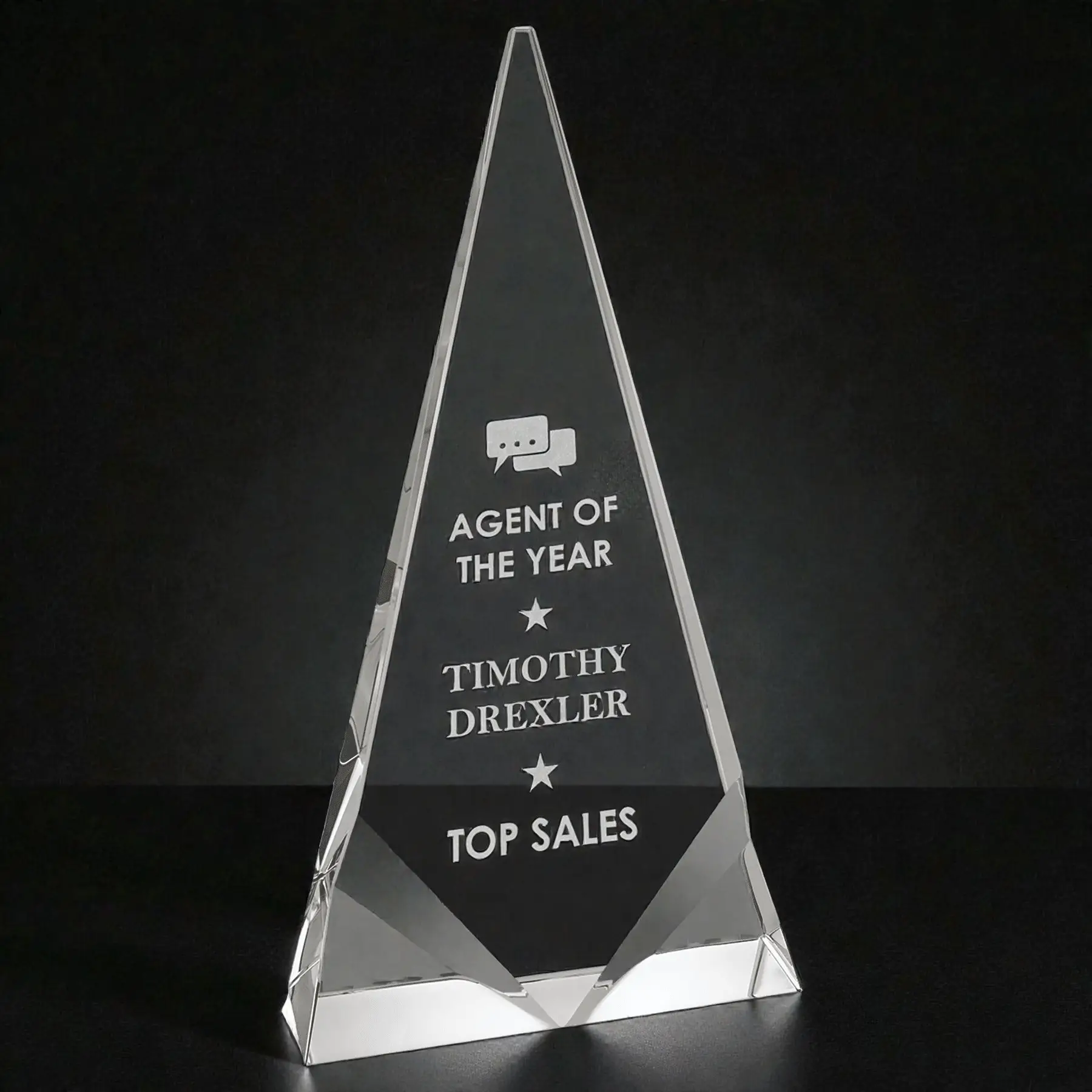 Our Crystal Triangle Award shown here in the CRY261L SKU, which is 5" x 9.5" in size and weighs3.5 lbs. It's shown here on a dark background which makes the frost white laser engraving pop. The middle area has laser engraving personalization and the bottom two corners have a decorative bevel front. This crystal trophy comes in a deluxe gift box & includes free engraving.