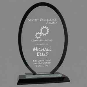 Regal Oval Black Glass Award (RGL16BK) – 9 inch tall elegant black-bordered glass trophy with custom laser engraving. Features 'Service Excellence Award' for Michael Ellis from GearHead Productions, with gear graphics. Modern oval design on a sleek black glass base, shown against a neutral gray background.